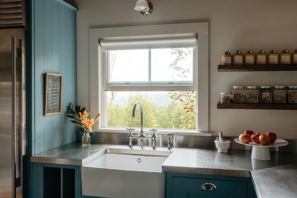 Farmhouse sink with stainless steel countertops and blue cabinets.