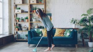 Woman mopping floor while wearing headphones.